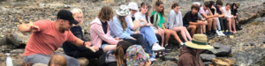 senior college students taking a break from hiking on a rocky outcrop
